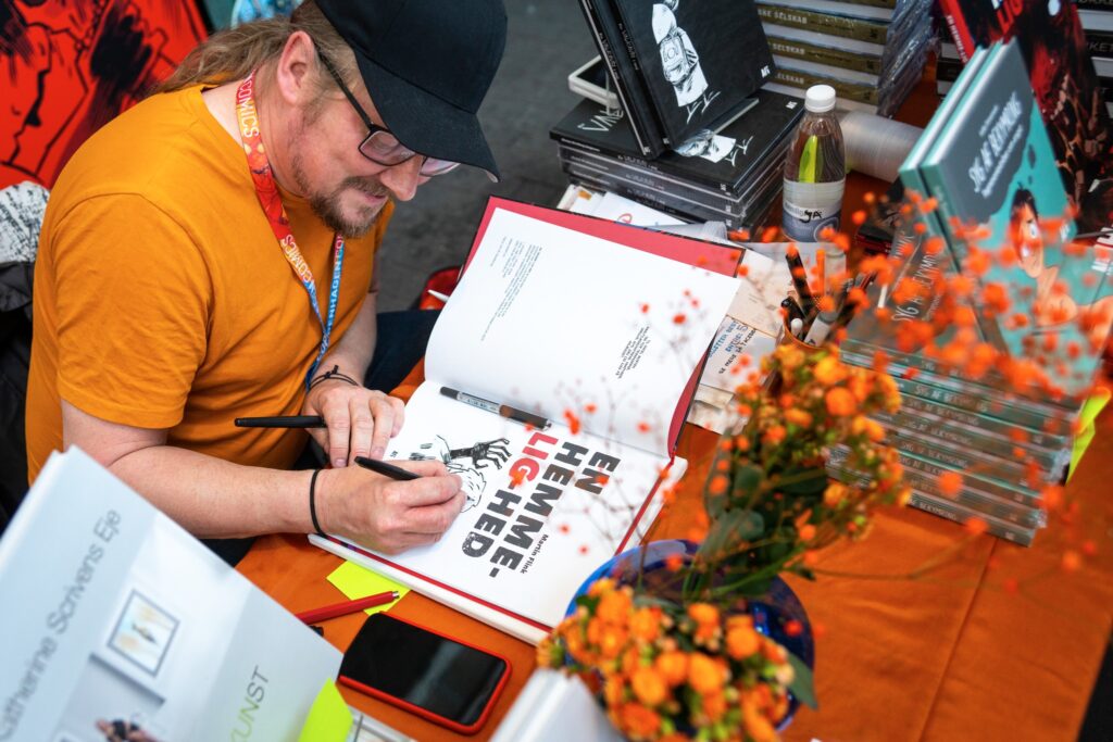 Martin Flink signing "En Hemmelighed" comic-book at release. Copenhagen Comics 2024.